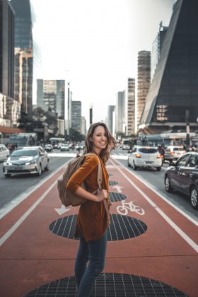 Vrouw met rugzak op fietspad omringt door auto's in stadsgezicht