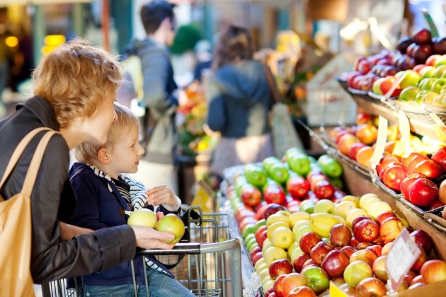 Moeder en zoon kijken in de supermarkt naar de soorten fruit die daar liggen.