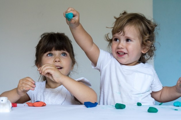 Twee peuters spelen met klei.